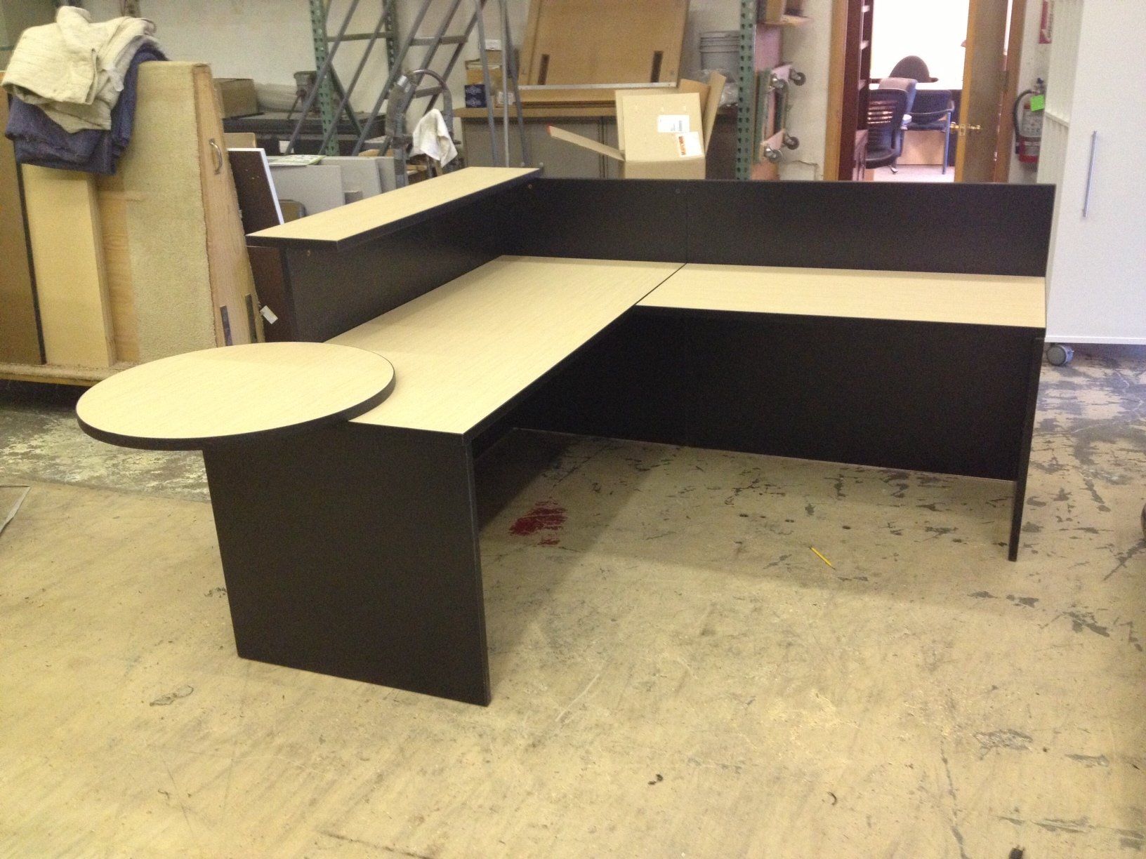 L-shaped black and tan desk with a round extension.