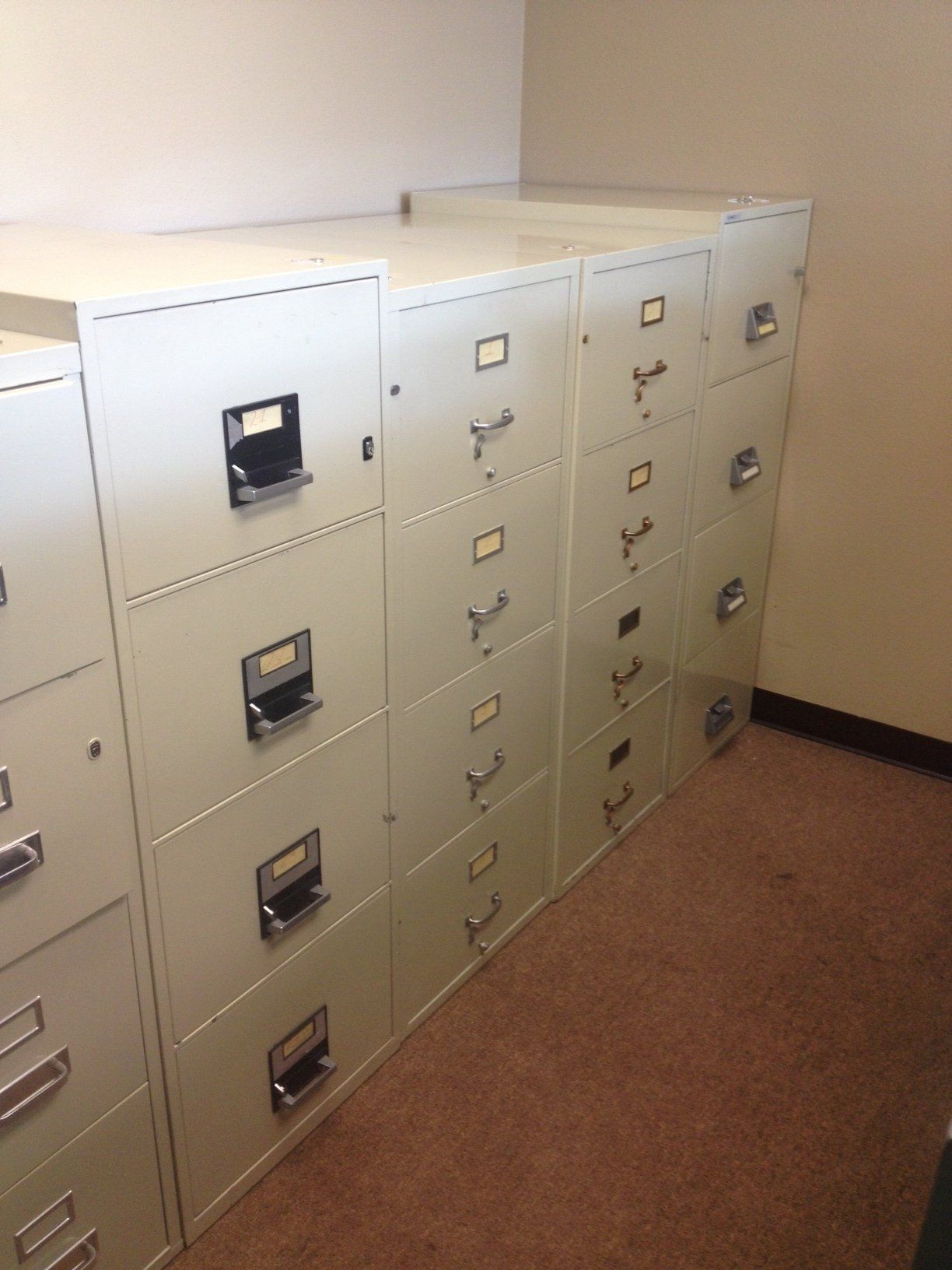 Row of beige filing cabinets in an office setting, arranged side-by-side.
