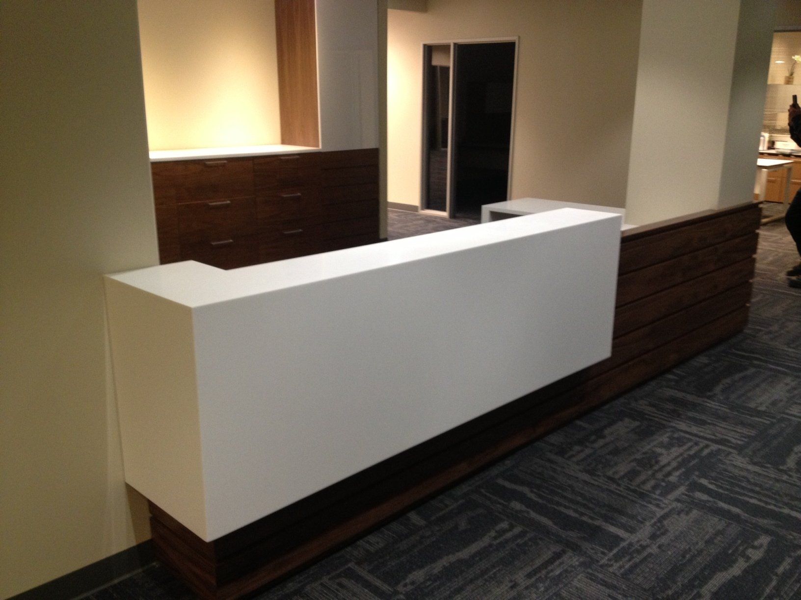 Modern white and wood reception desk in office setting.