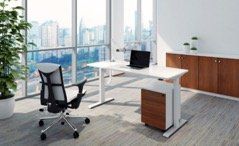 Modern office with a white standing desk, black ergonomic chair, and cityscape view through large windows.