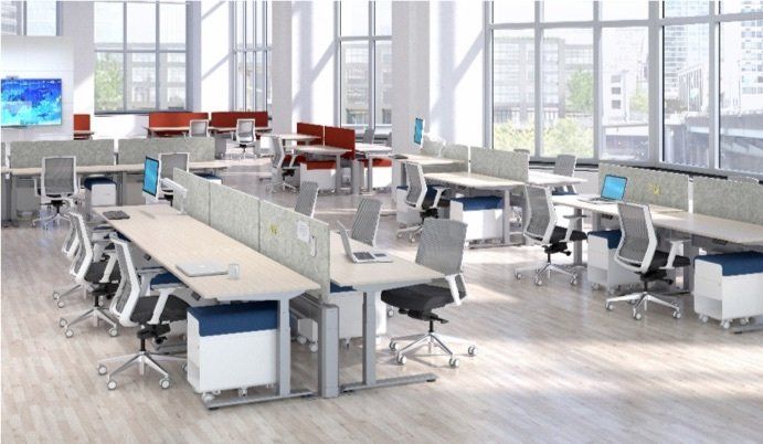 Open-plan office with desks, chairs, and computers. Neutral tones with red accents, large windows, and natural light.