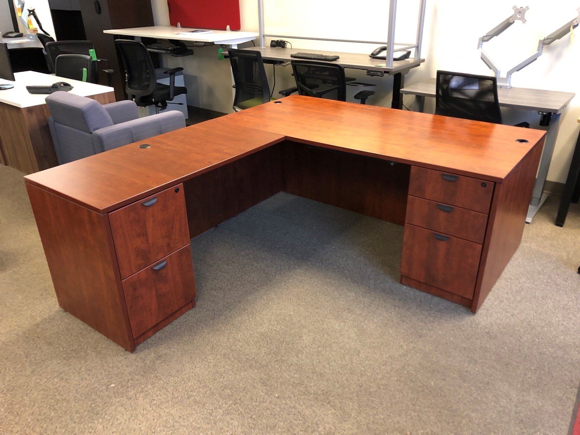 L-shaped cherry-wood desk with two drawer units, in an office.