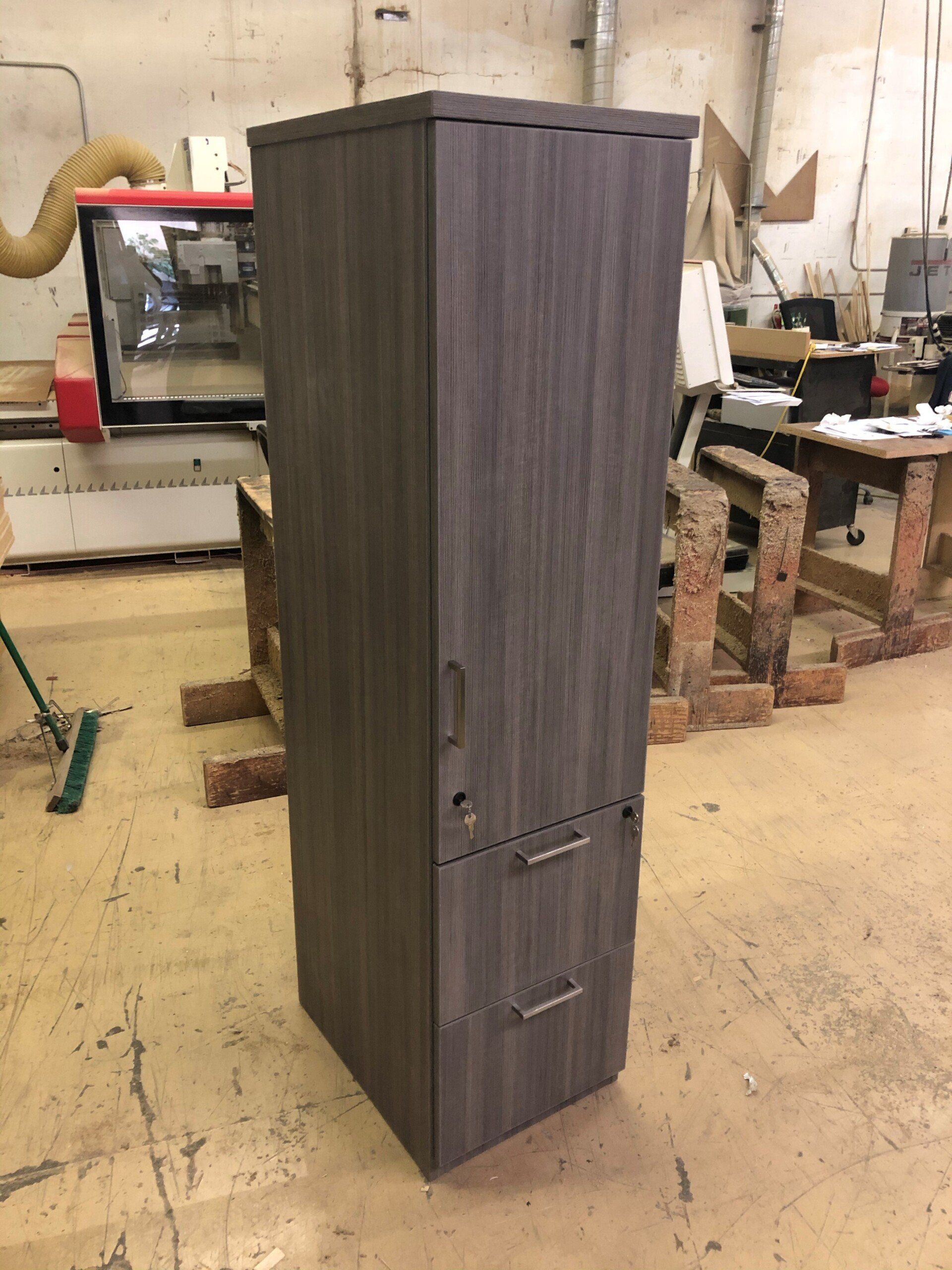 Tall dark gray storage cabinet with drawers in a workshop setting.