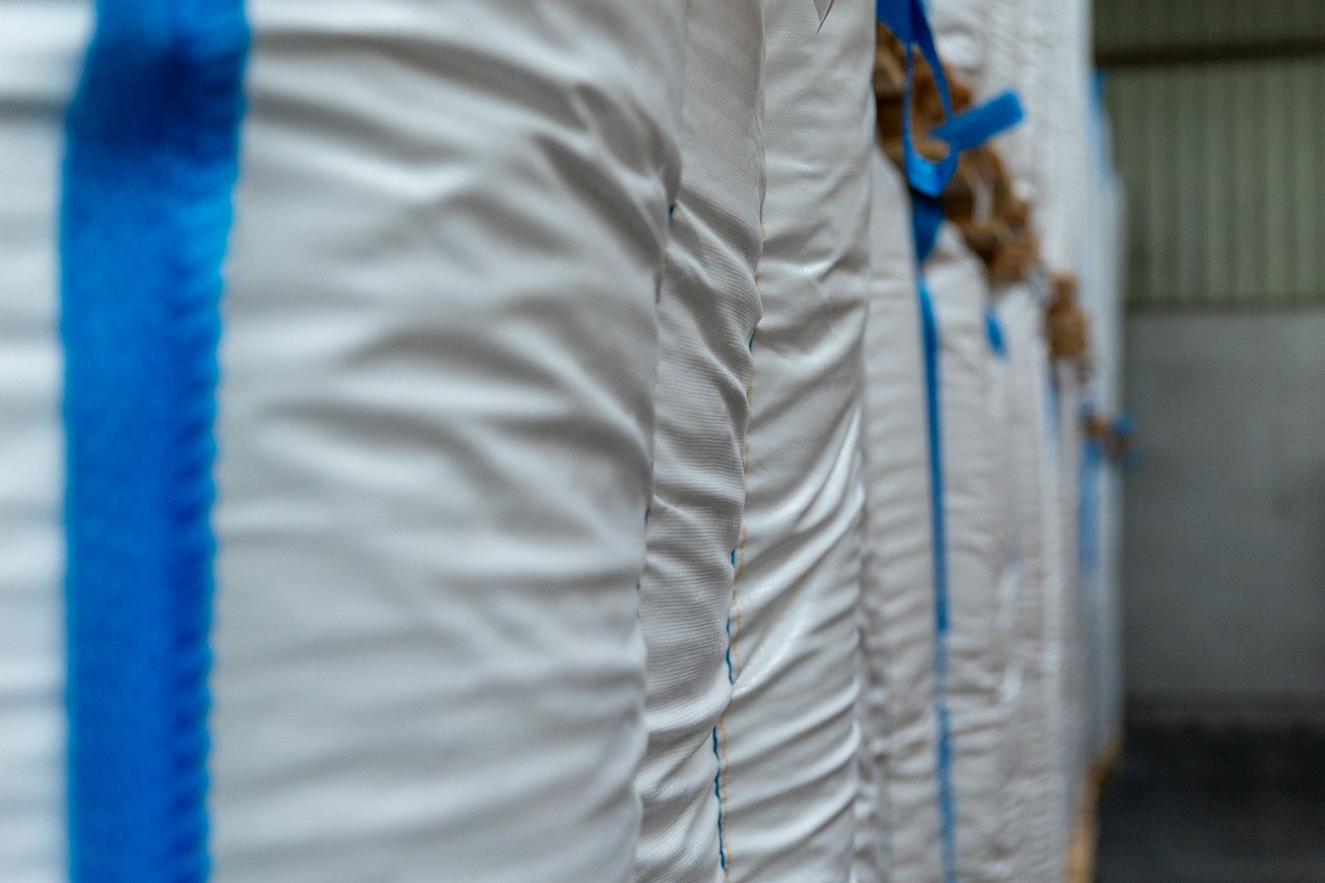 Een rij witte tassen met blauwe banden in een pakhuis.