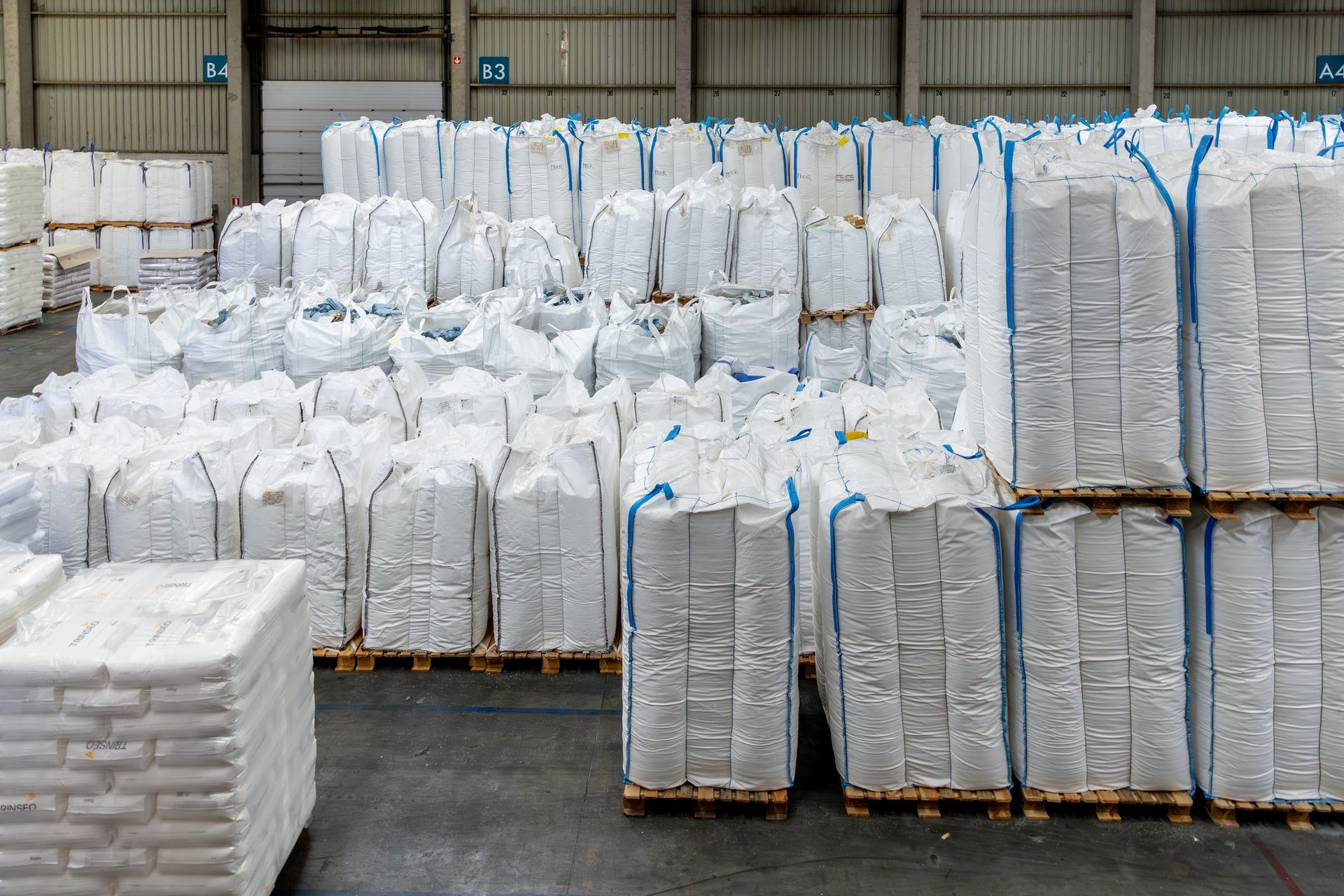 Een magazijn vol met witte zakken en pallets.