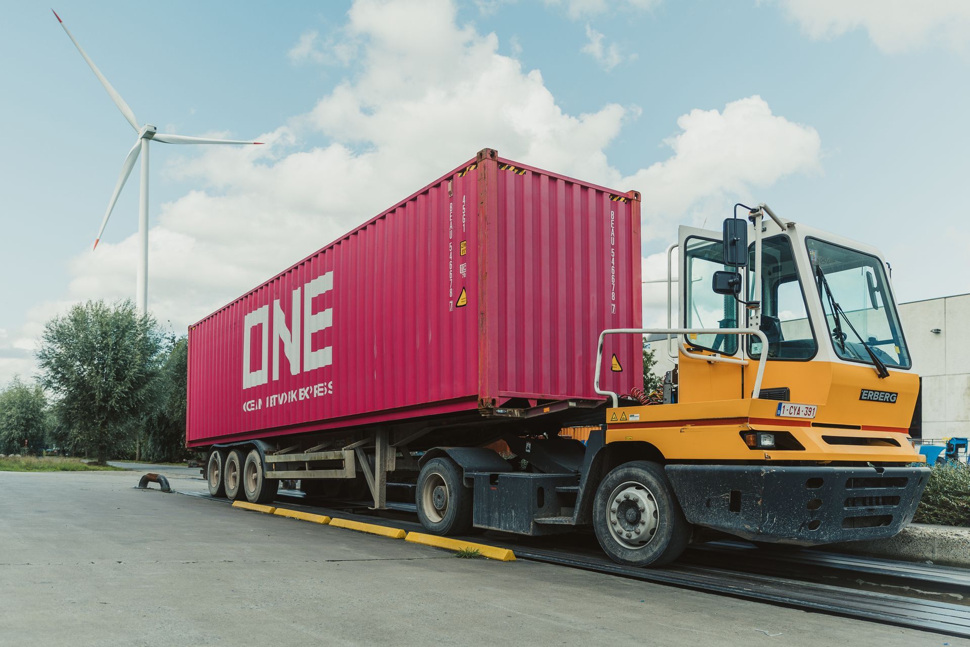 Een rode vrachtwagen met het woord one op de zijkant staat geparkeerd naast een gele vrachtwagen.