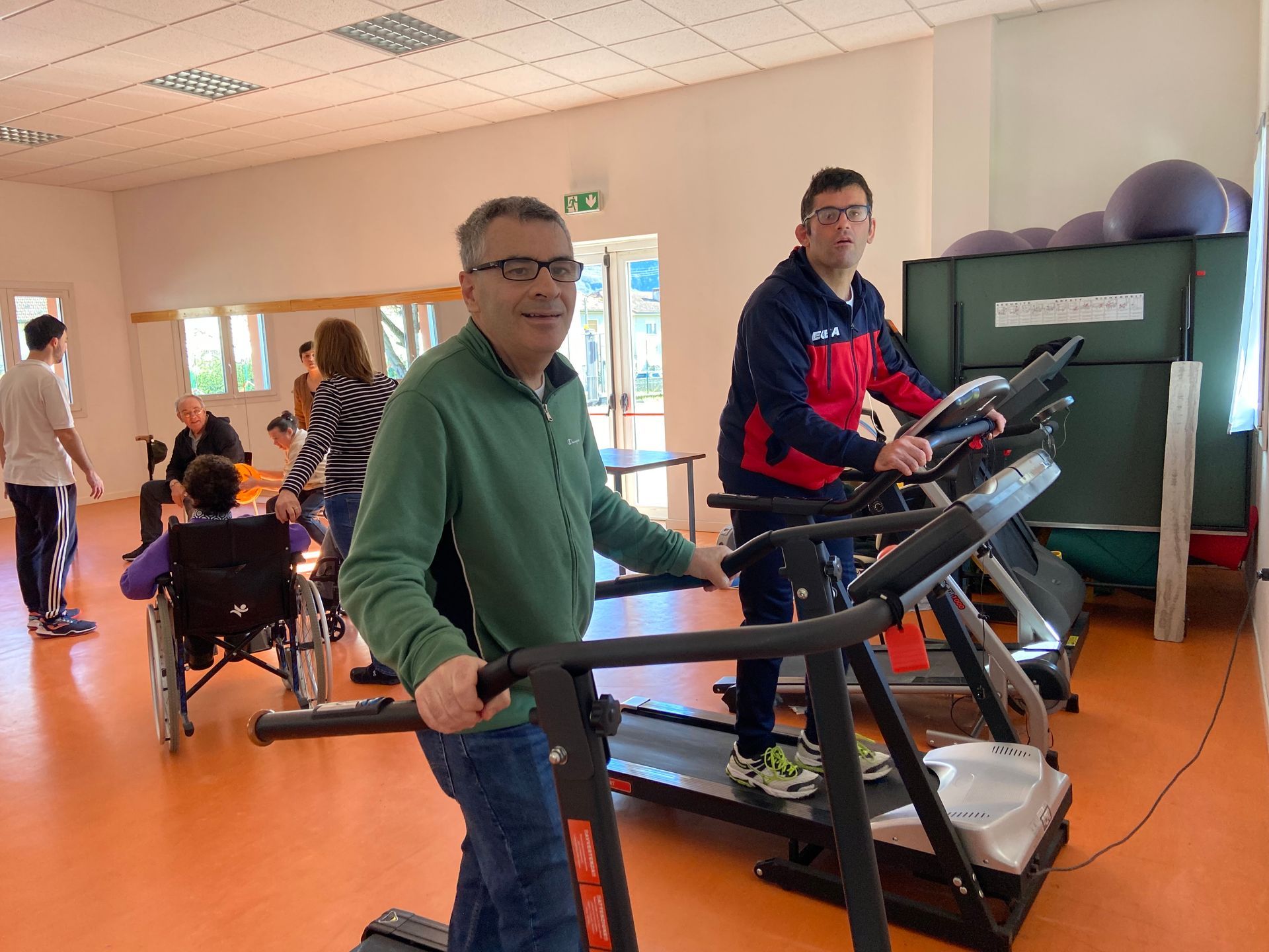 Due uomini stanno pedalando sul tapis roulant in una palestra.