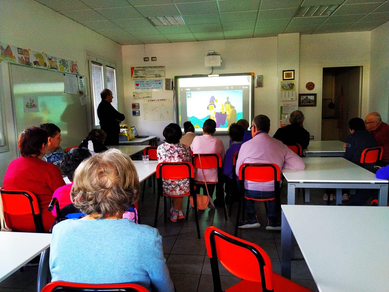 Un gruppo di persone è seduto in un'aula e guarda una presentazione