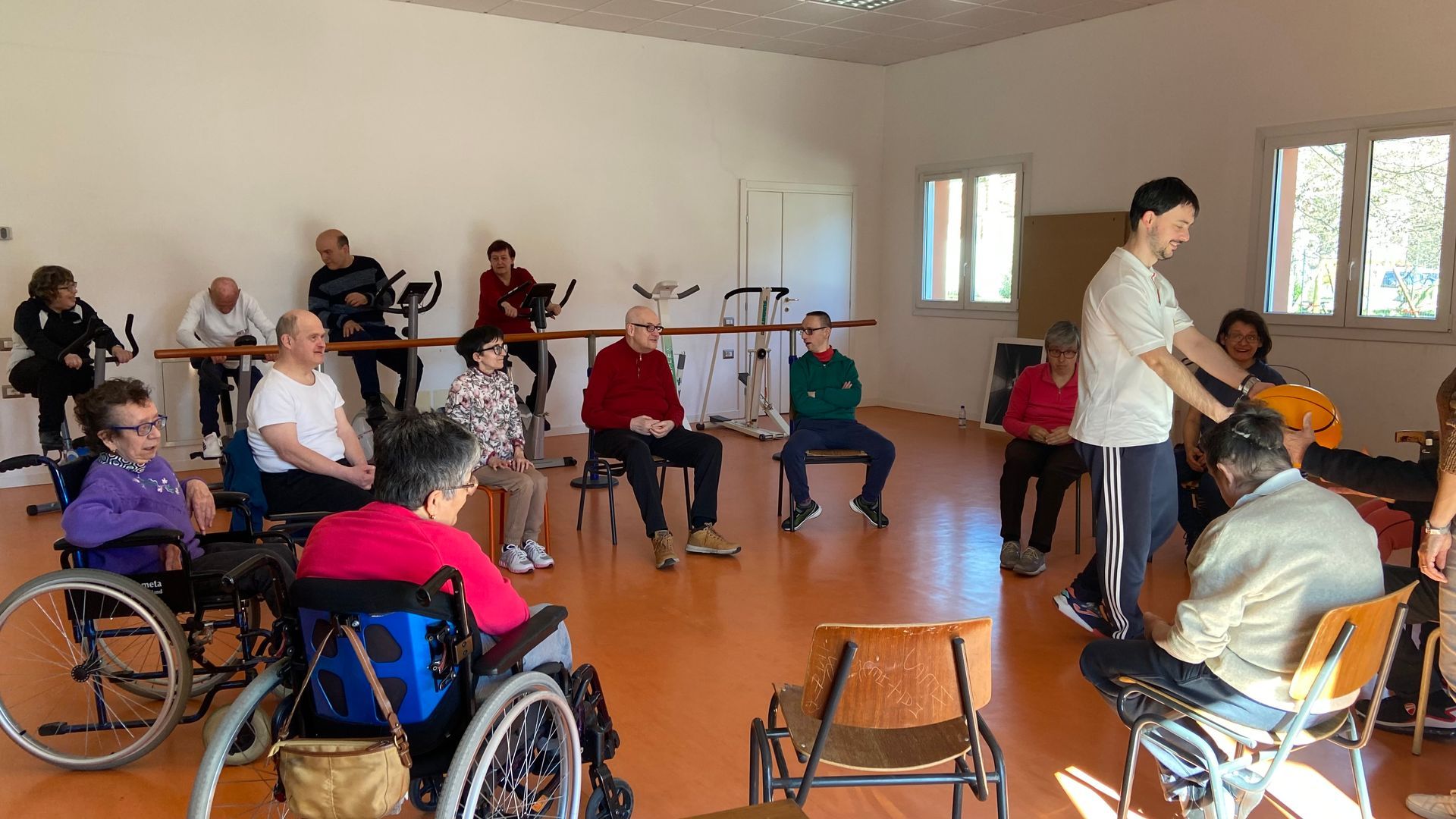 Un gruppo di persone su sedia a rotelle è seduto in una stanza.