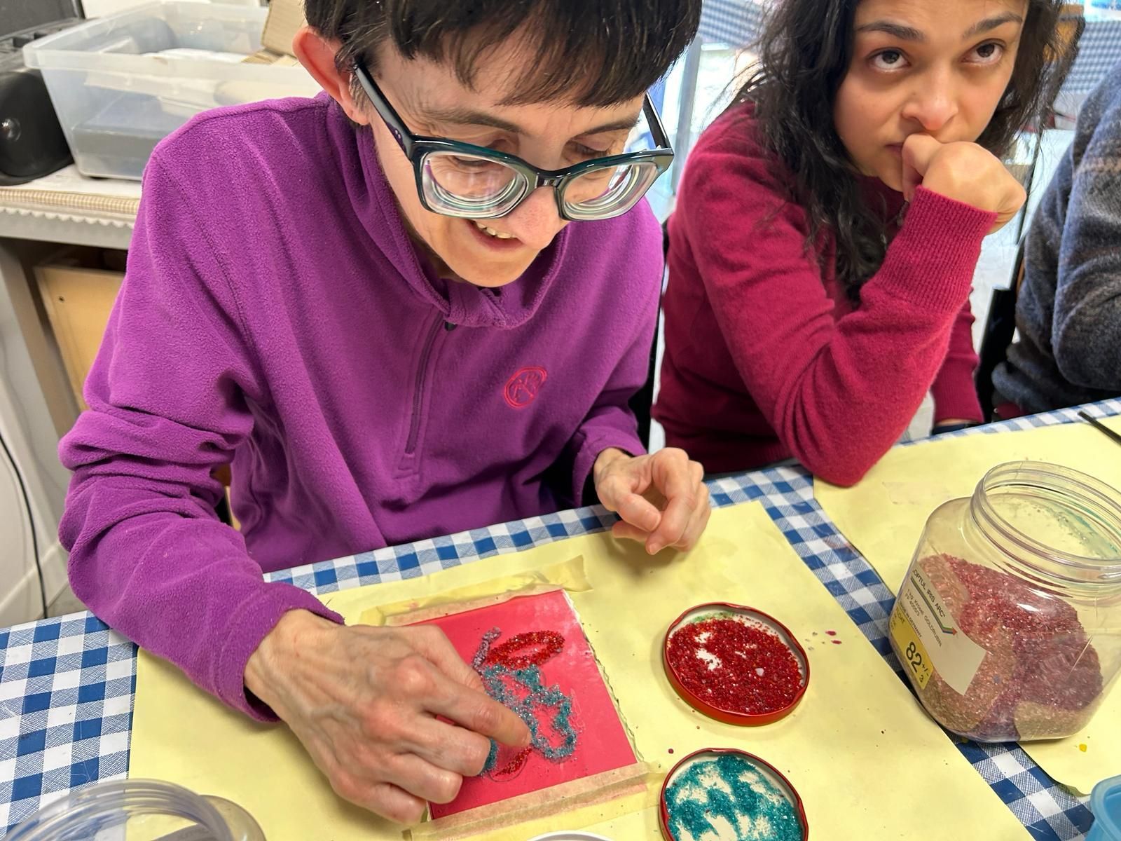 Un ragazzo e una donna sono seduti a un tavolo e fabbricano gioielli.