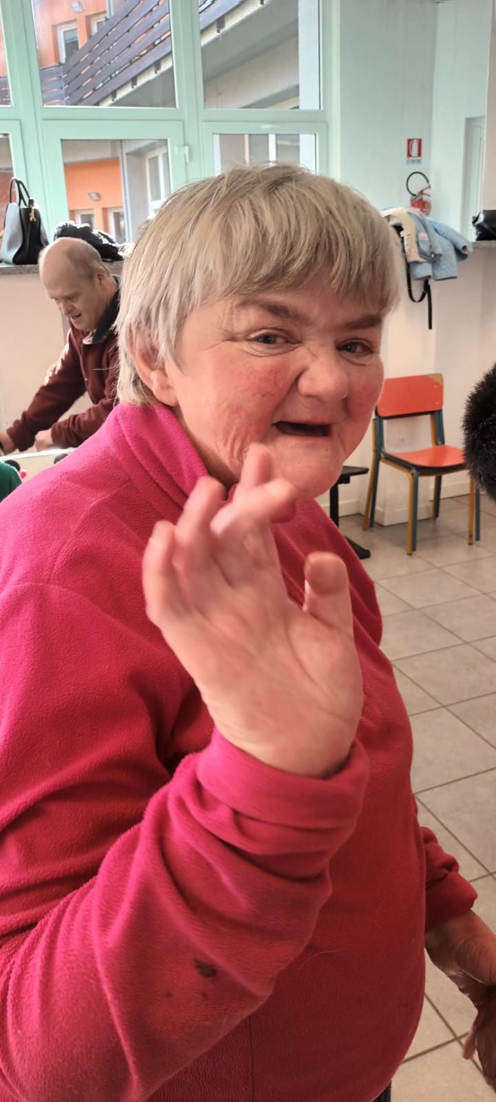 Una donna con un maglione rosa sta facendo una faccia buffa.