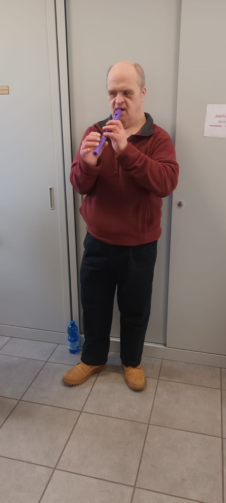 Un uomo è in piedi in una stanza e suona un flauto.