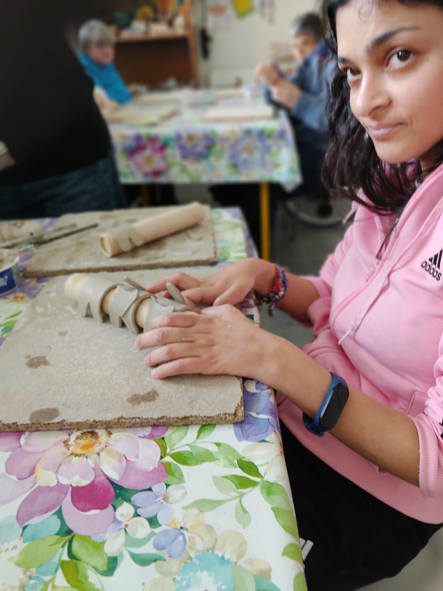 Una donna con una giacca adidas rosa è seduta a un tavolo