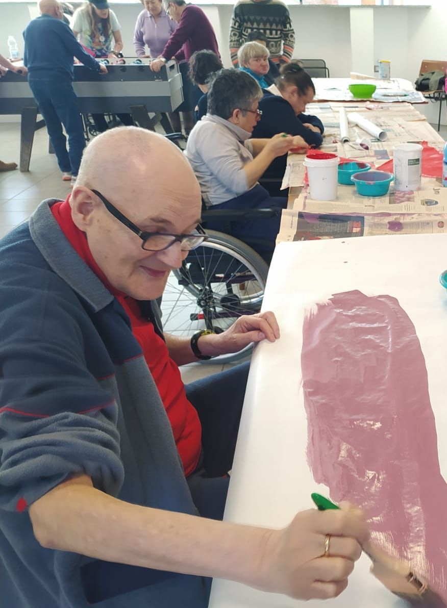 Un uomo su una sedia a rotelle è seduto a un tavolo e dipinge
