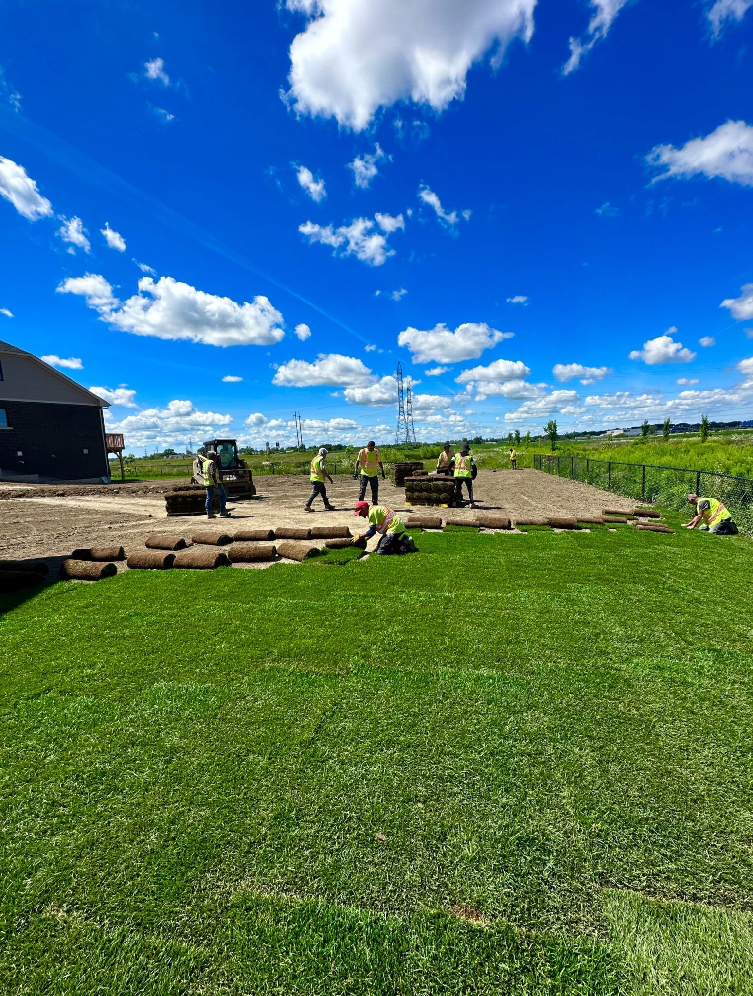 A group of people are working on a lush green lawn.