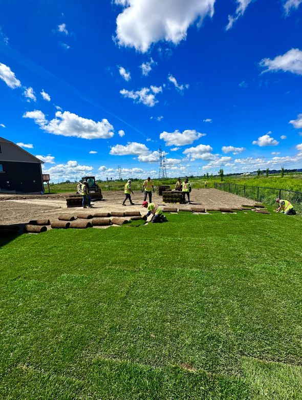 A group of people are working on a lush green lawn.