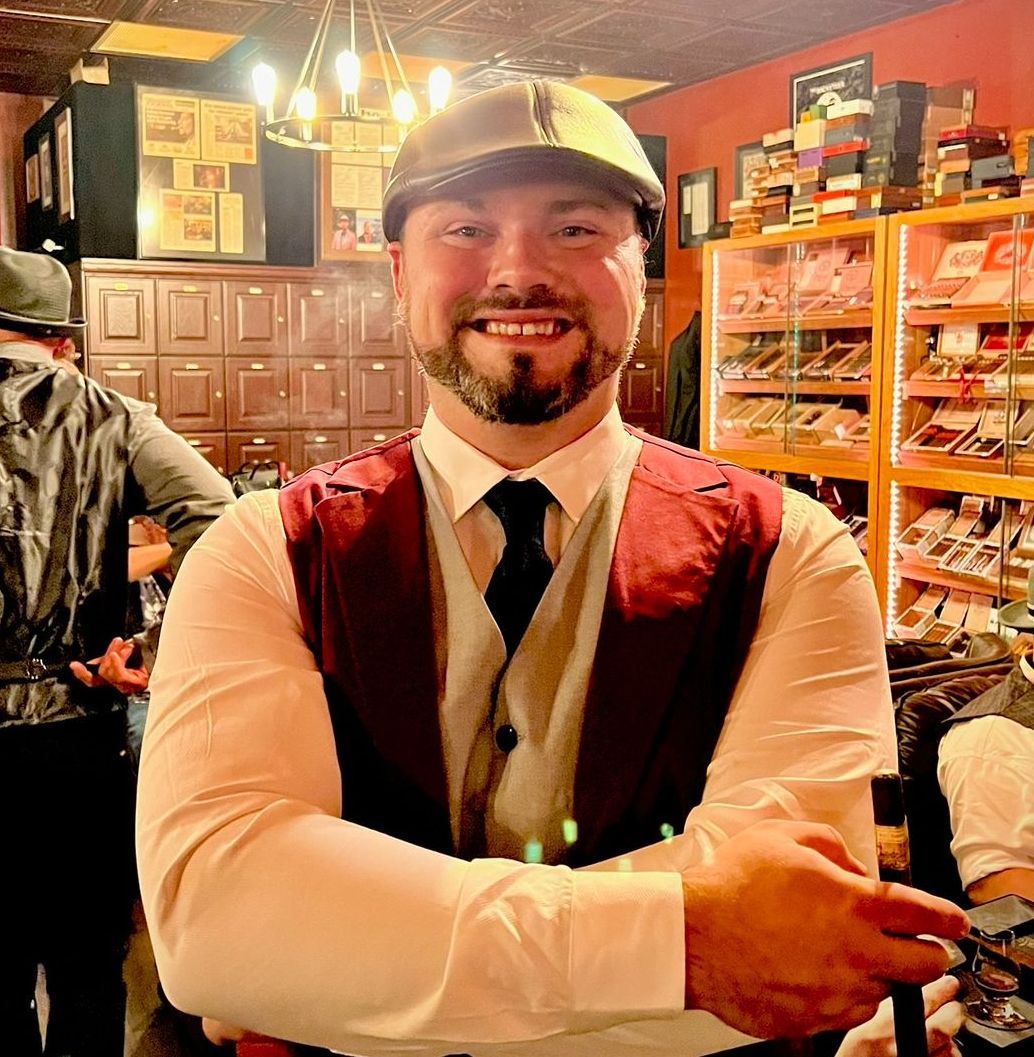 A man with a beard wearing a hat and vest