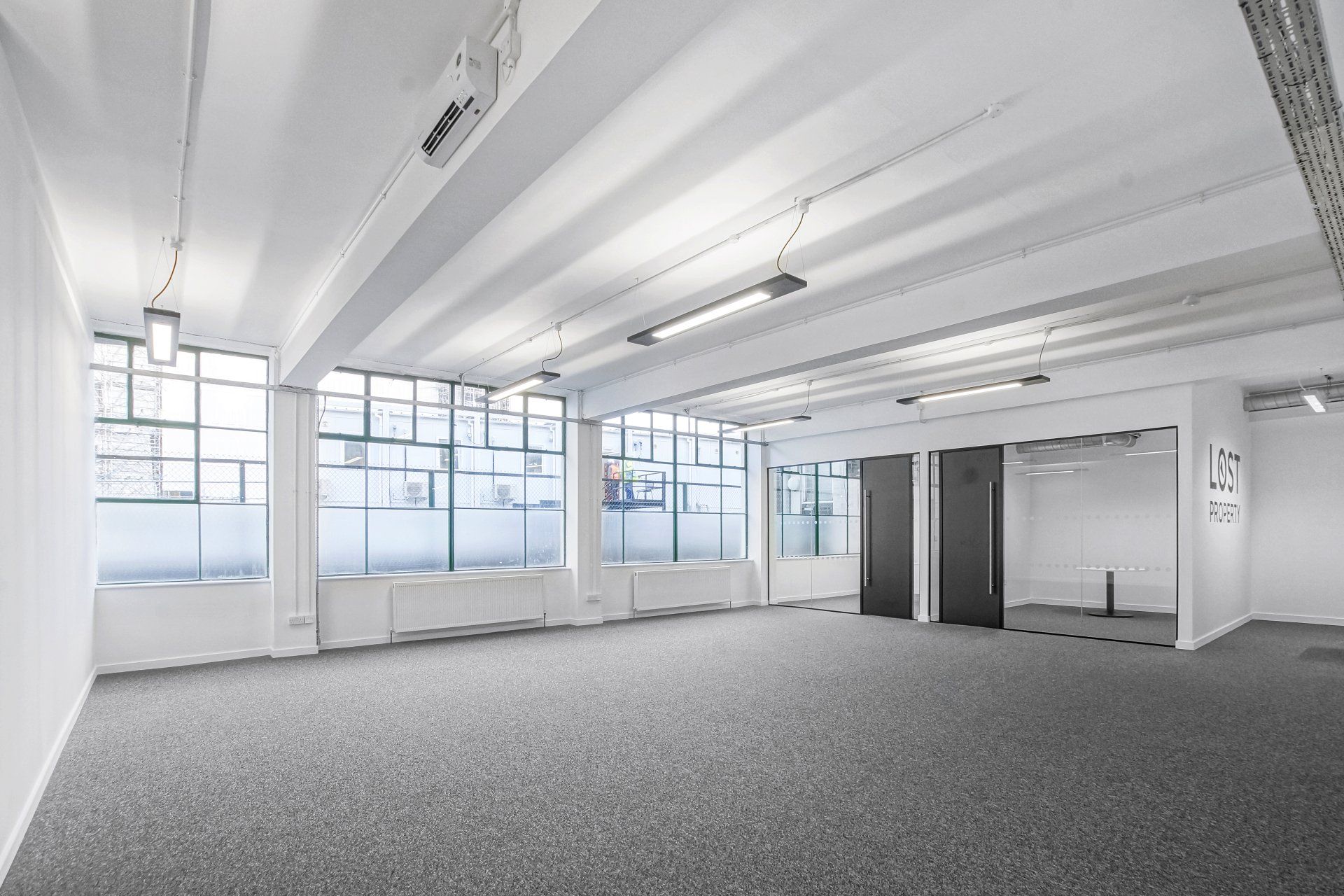 A large empty room with a lot of windows and a carpeted floor.