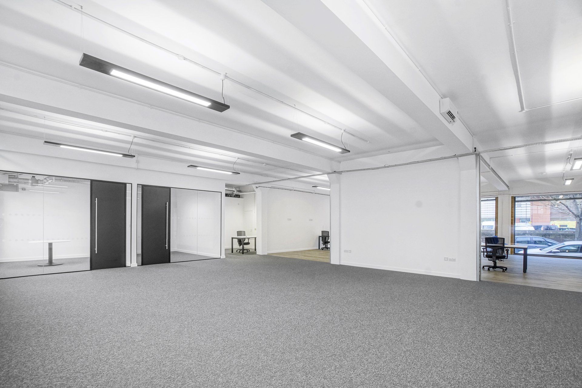 A large empty office space with a carpeted floor and white walls.