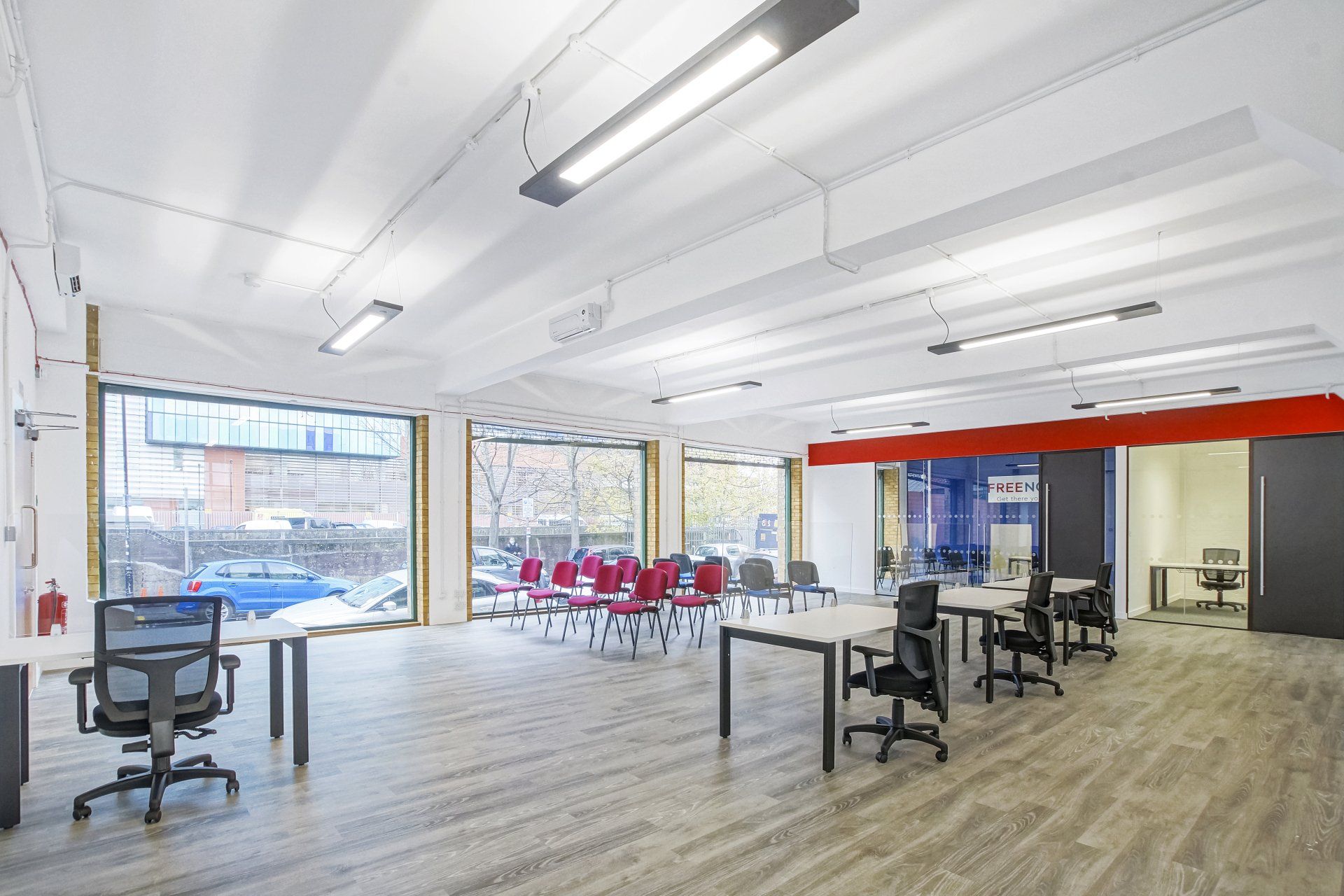 A large empty office with tables and chairs and a lot of windows.