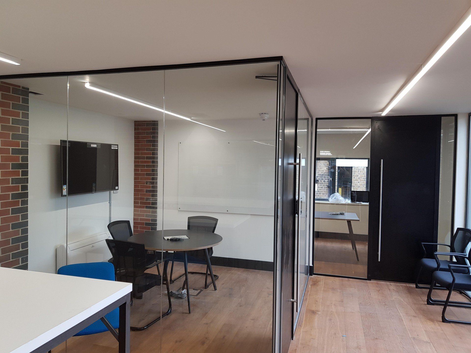 A conference room with a table and chairs and a television on the wall.