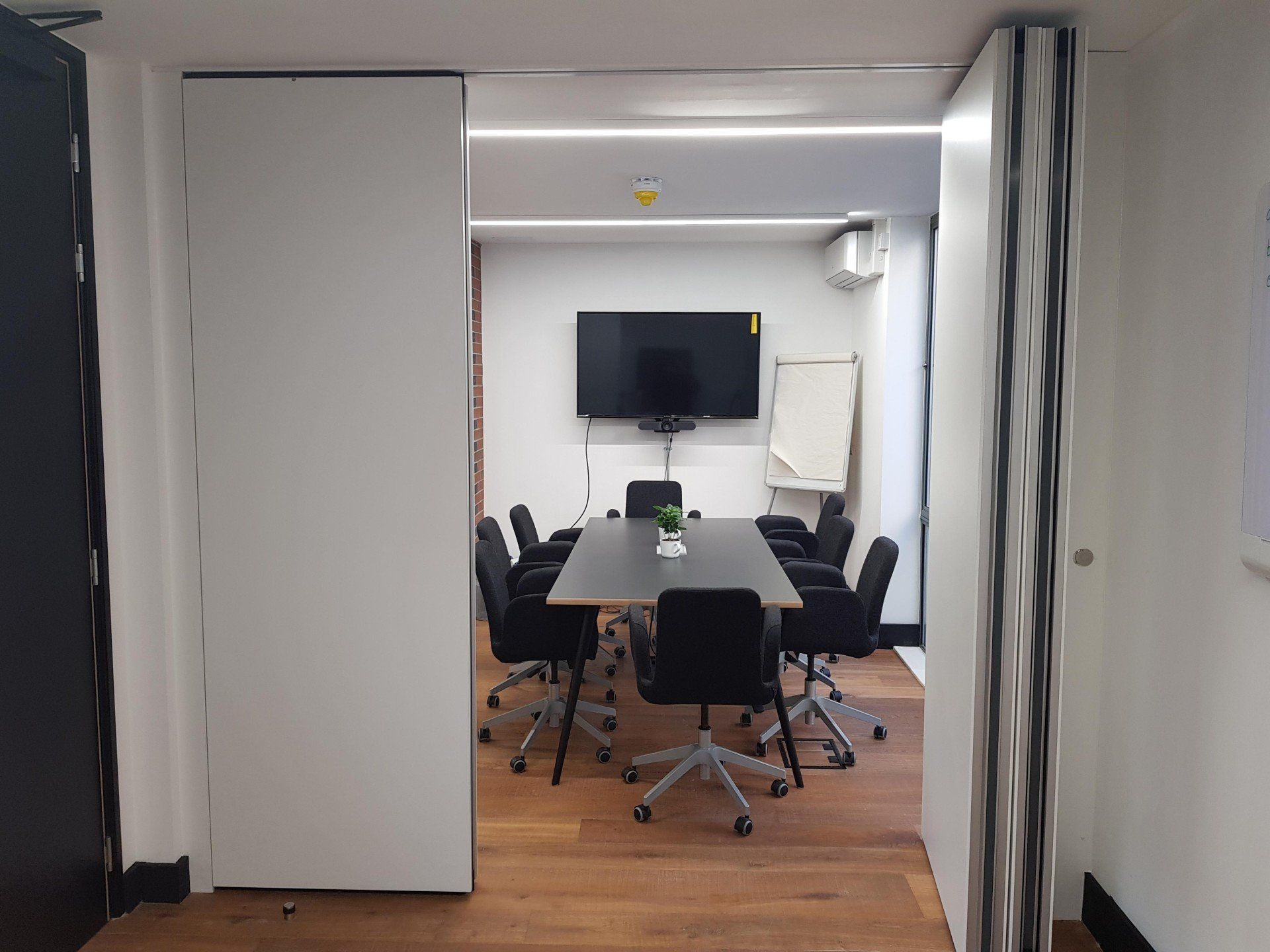 A conference room with a table and chairs and a flat screen tv.