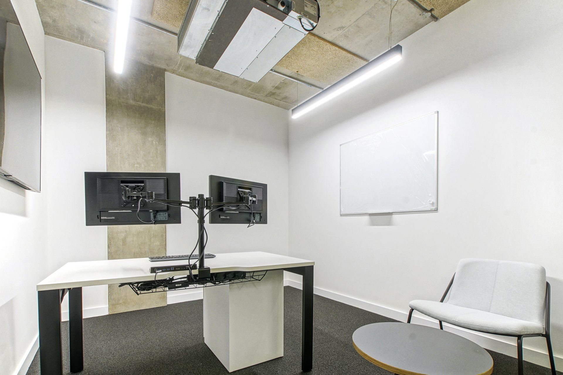 There are two monitors on the desk in the room.