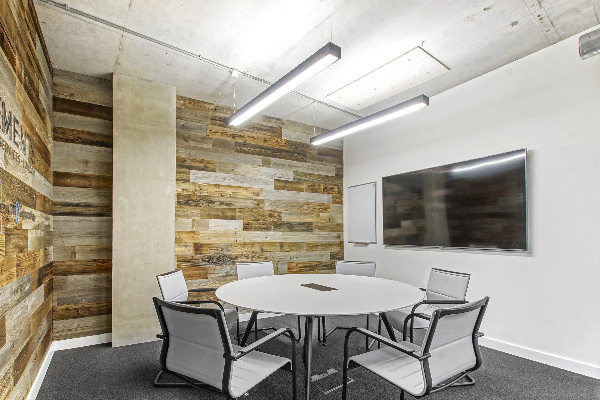 A conference room with a round table and chairs and a flat screen tv.