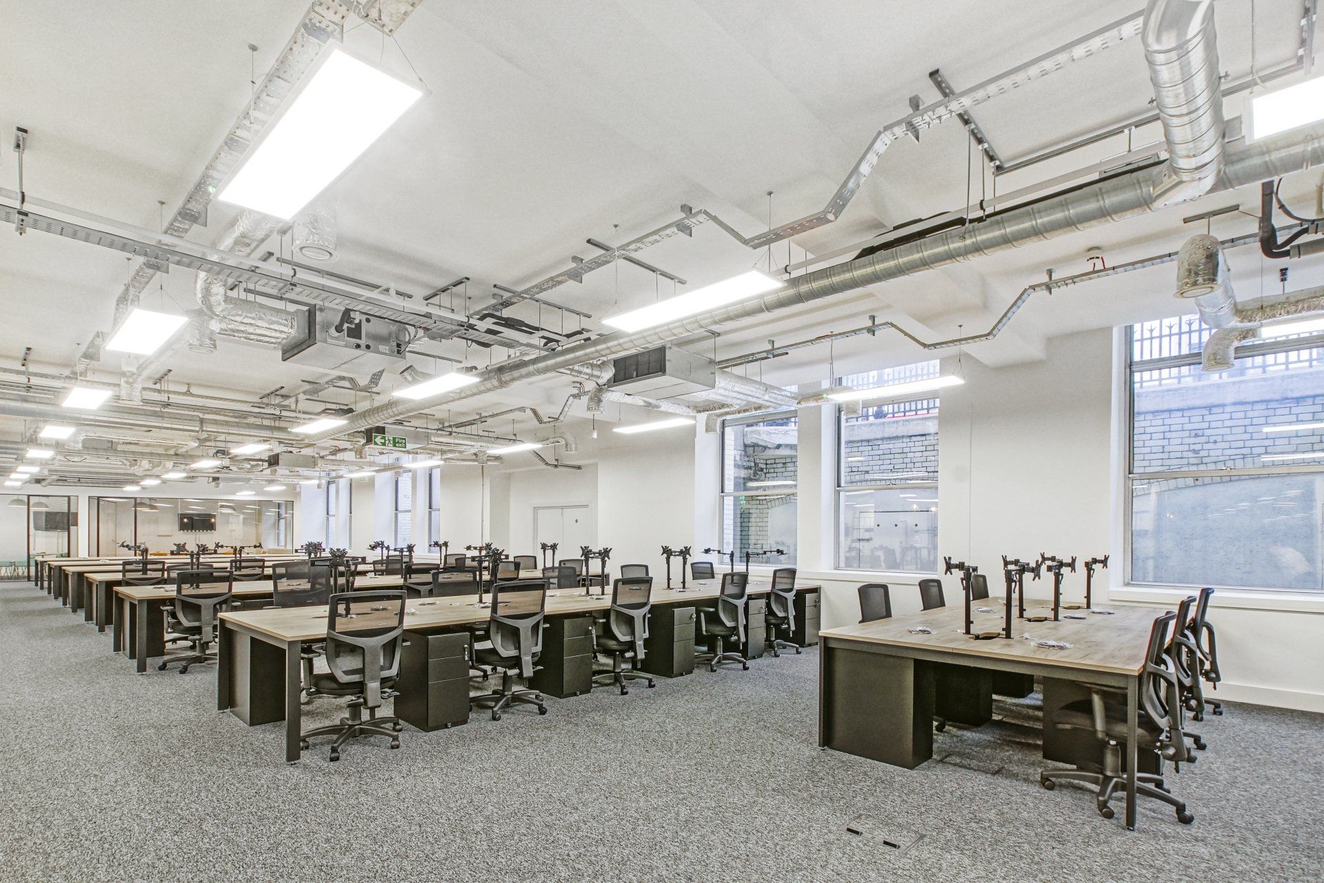 A large empty office with a lot of desks and chairs.