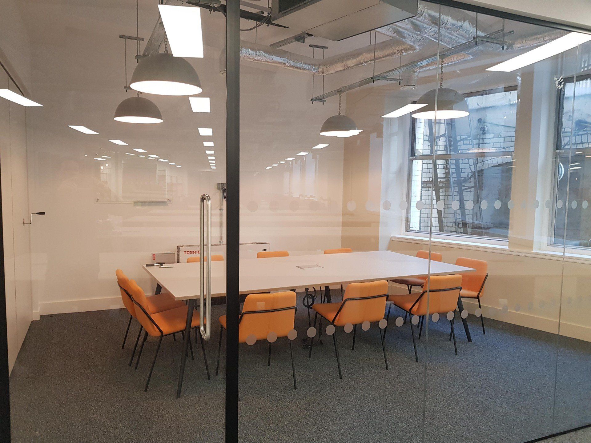 A conference room with a table and chairs behind a glass wall.