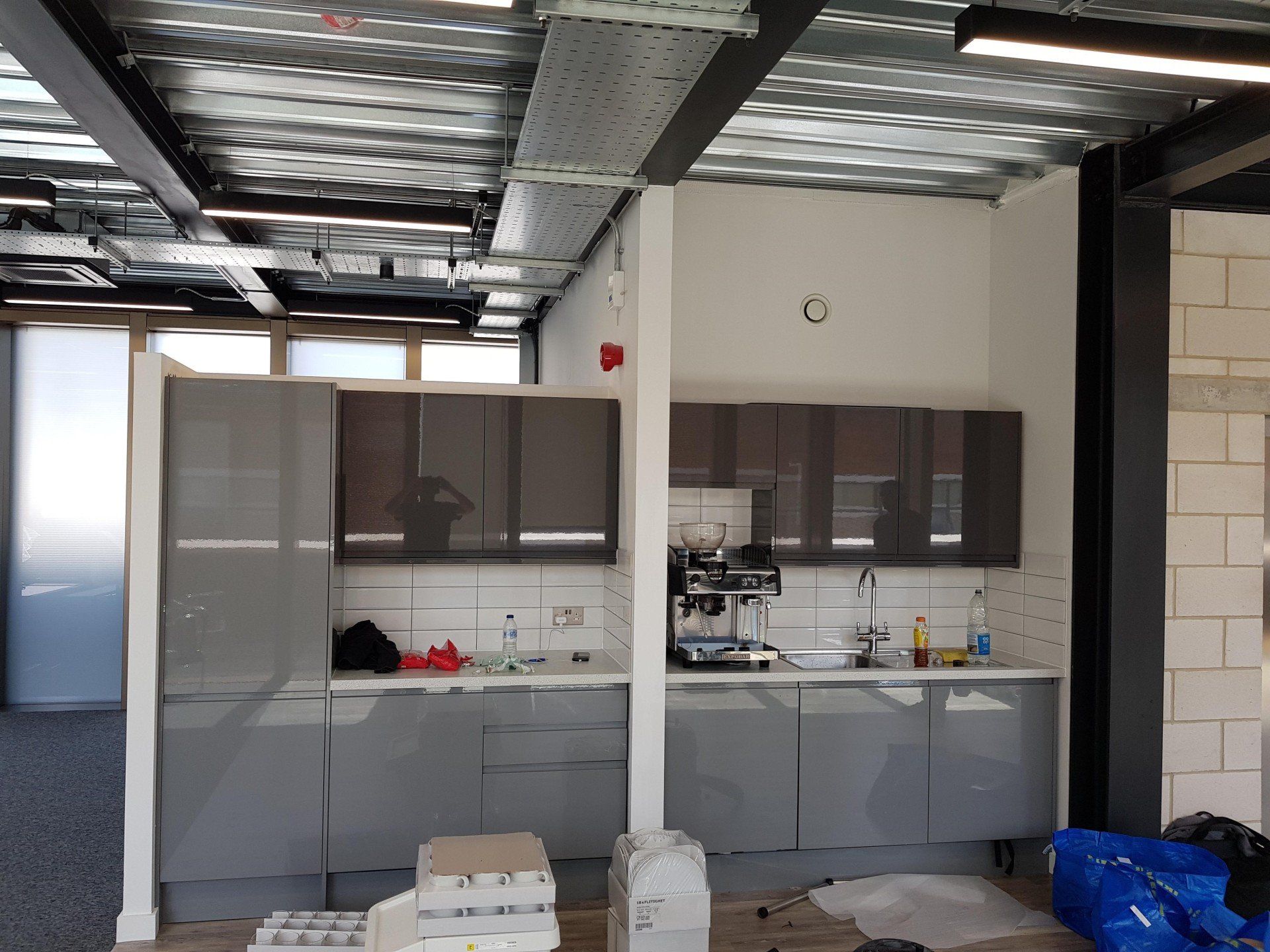 A kitchen with gray cabinets and a blue bag on the floor