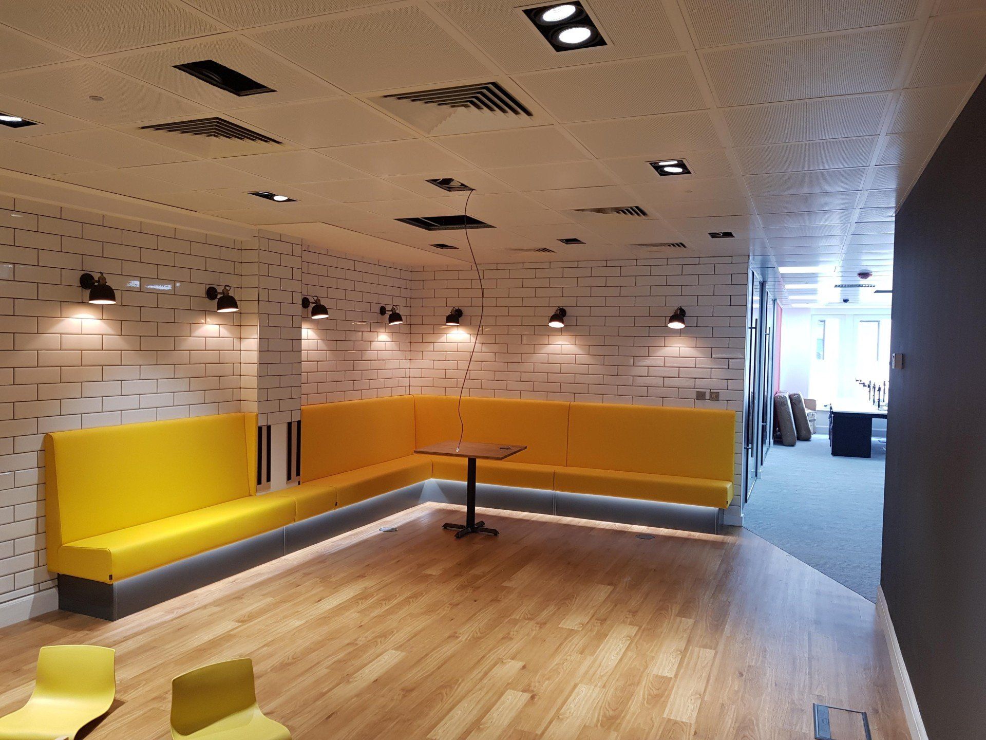 A room with a yellow bench and a table