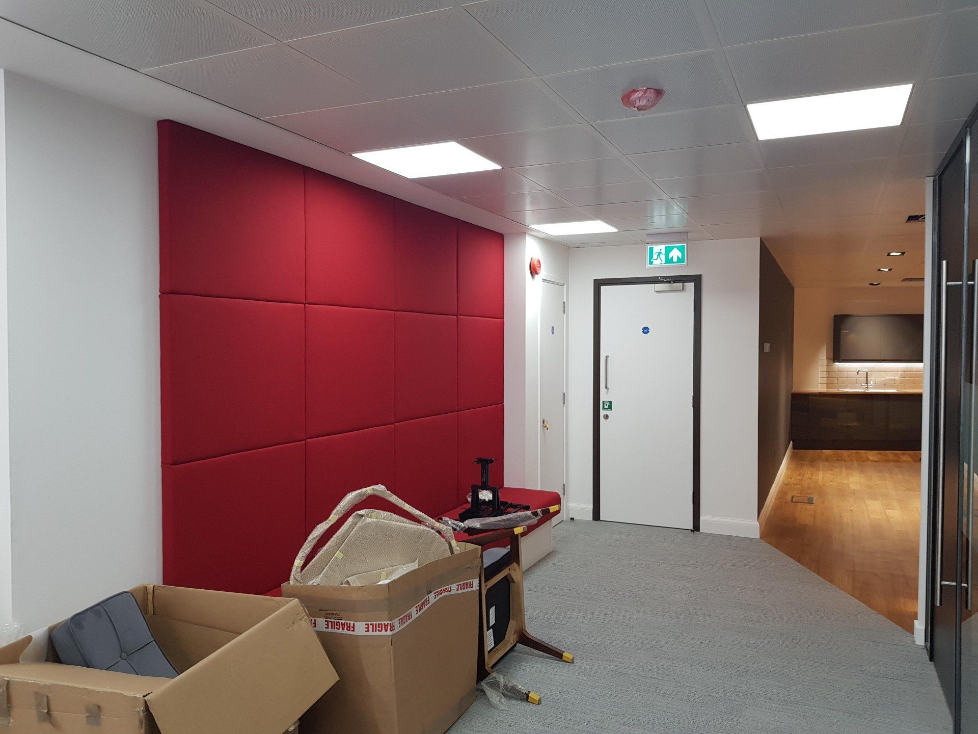 A hallway with a red wall and a white door