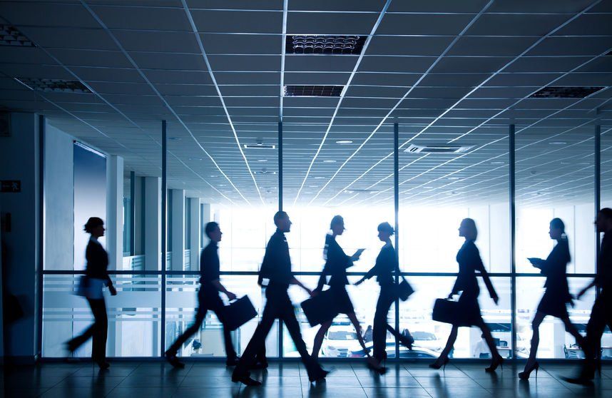 A group of people are walking down a hallway in an office building.