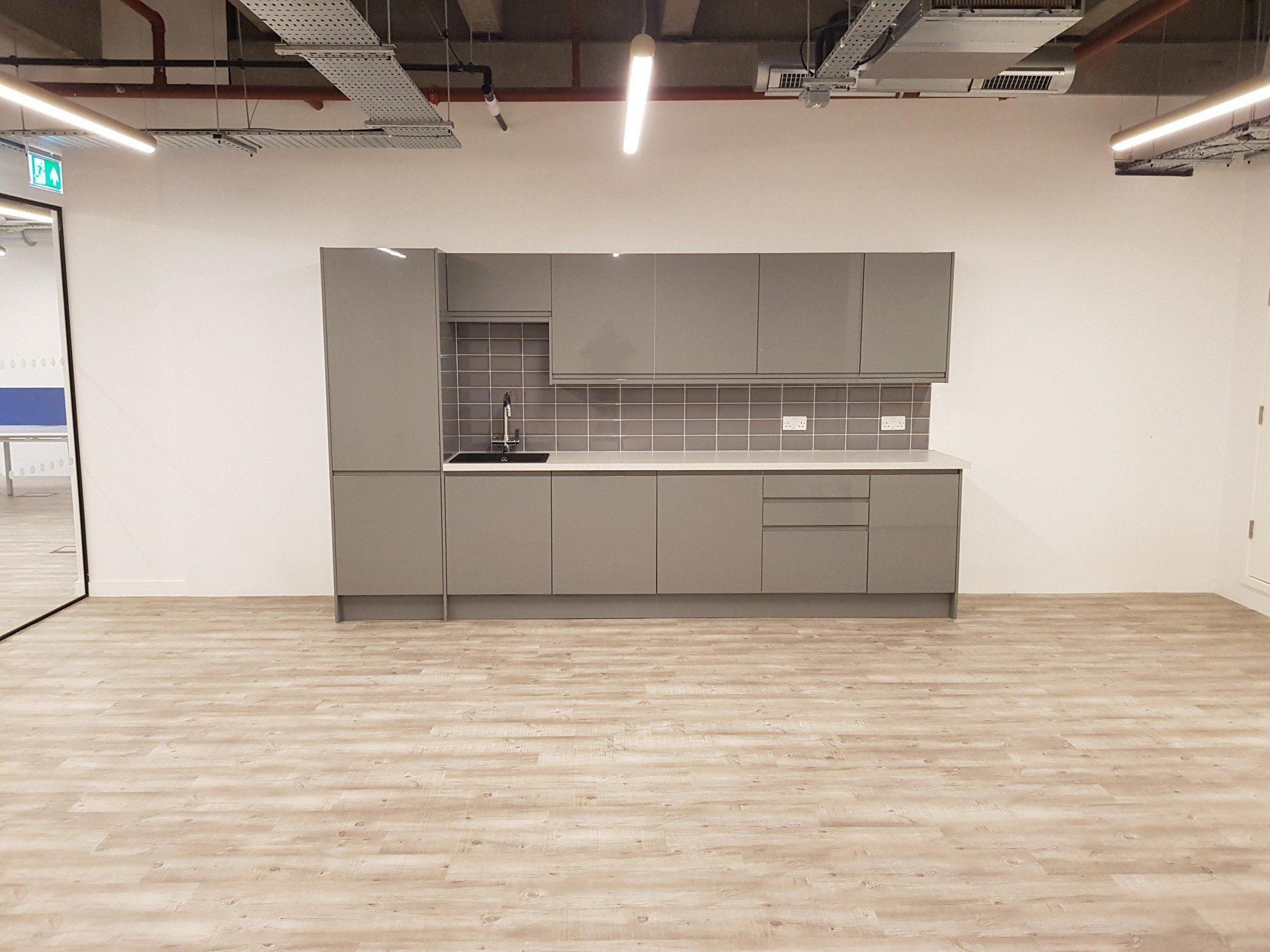 An empty kitchen with gray cabinets and a wooden floor.