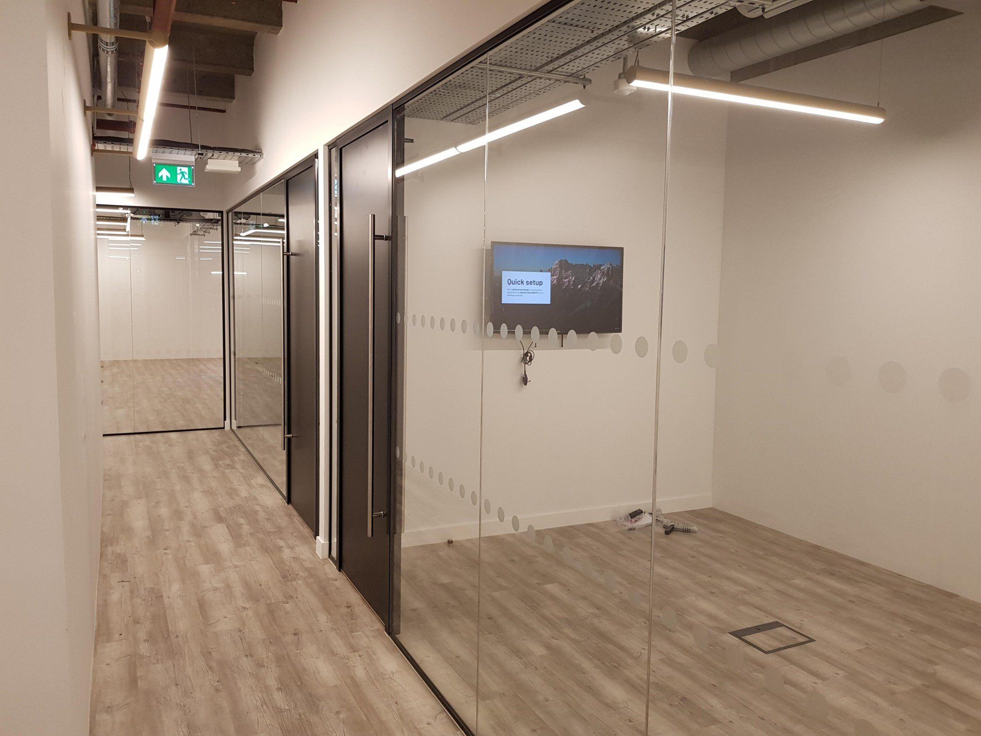 A hallway with a glass wall and a flat screen tv on the wall.
