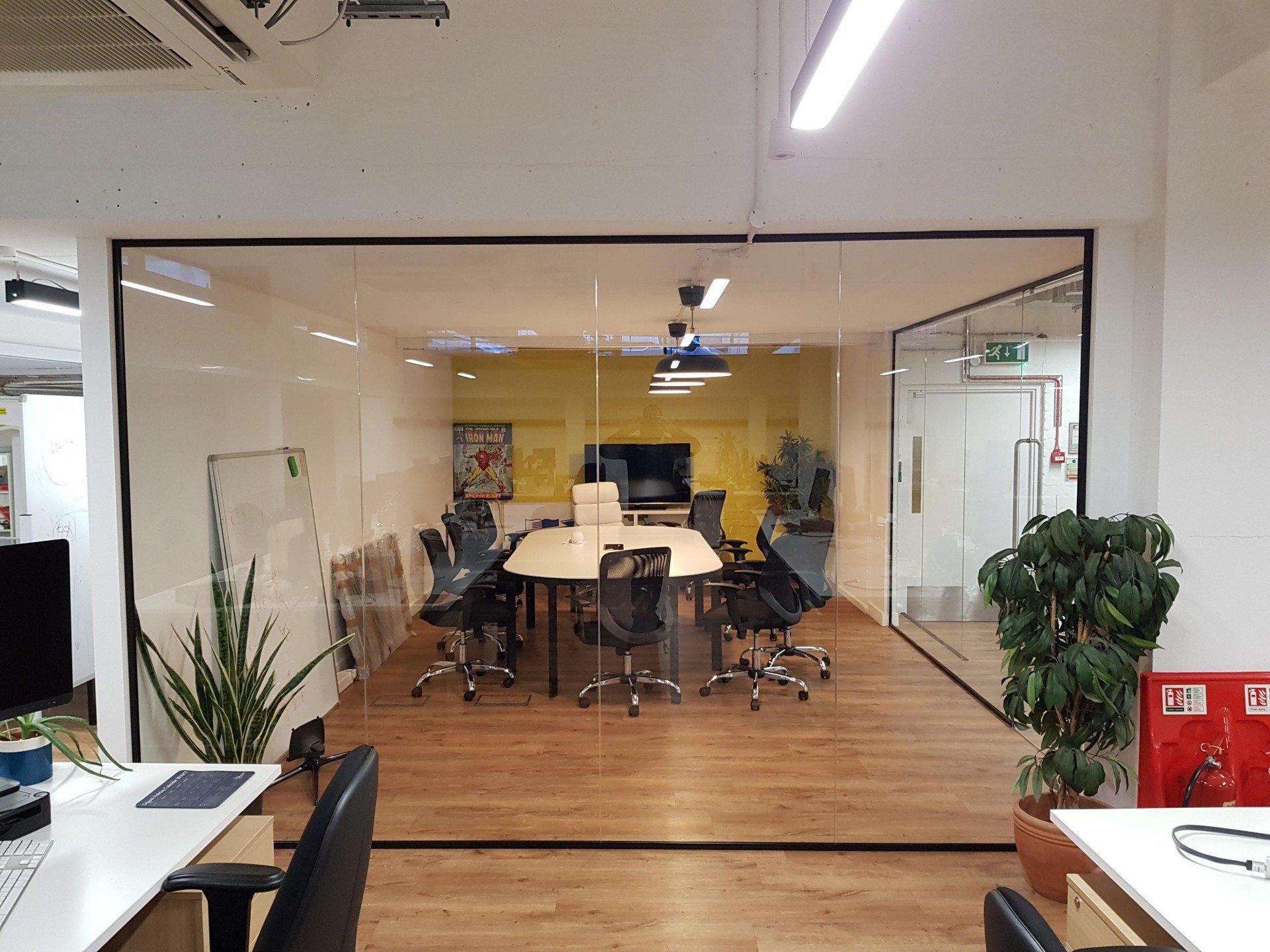 A conference room with a glass wall and a table and chairs.