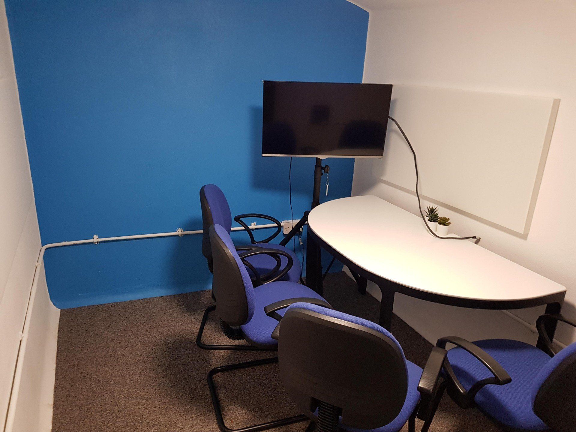 A conference room with a table and chairs and a flat screen tv.