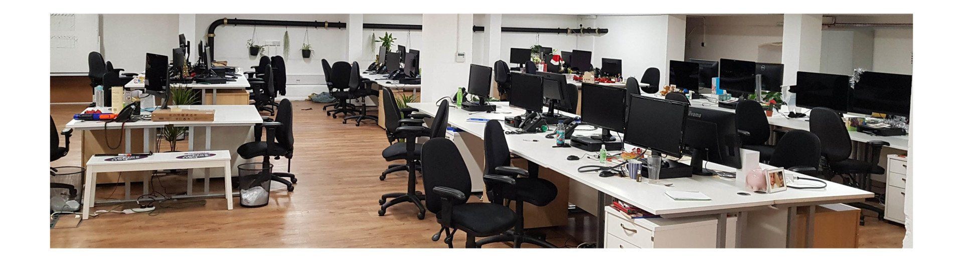 A large office with lots of desks and chairs and computers.