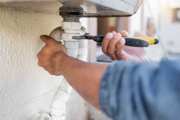 A plumber is fixing a sink pipe with a wrench.