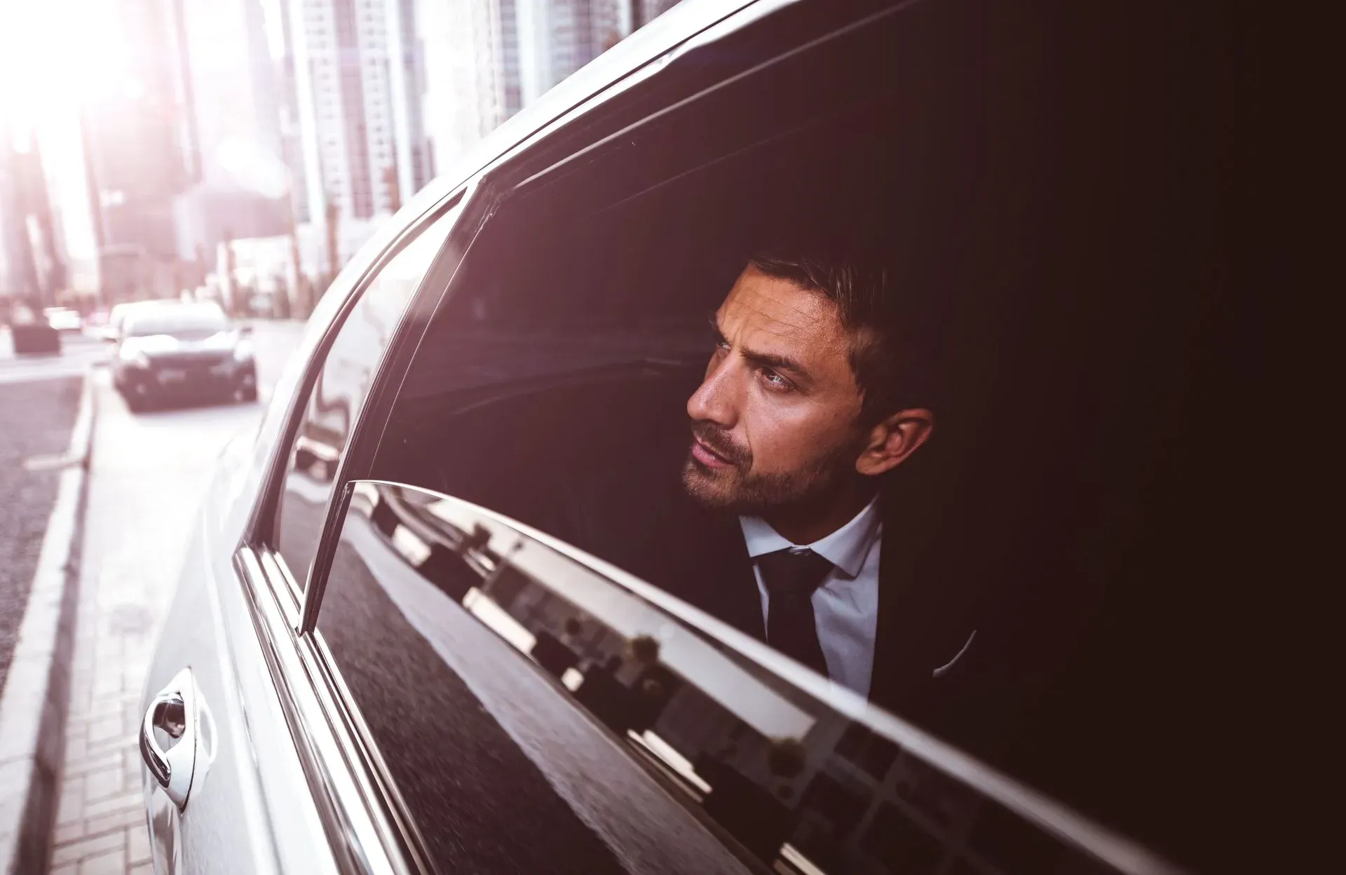 Professional businessman in suit and tie sitting in luxury limousine on city street