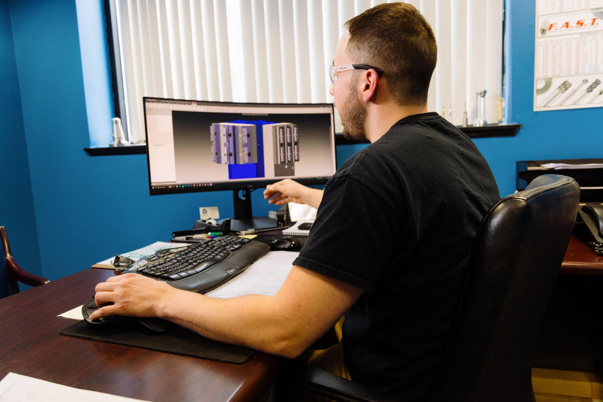 A man is sitting at a desk in front of a computer monitor.