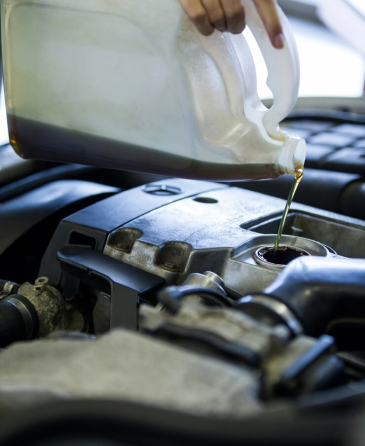 A person is pouring oil into a car engine. | Wind River Auto & Diesel
