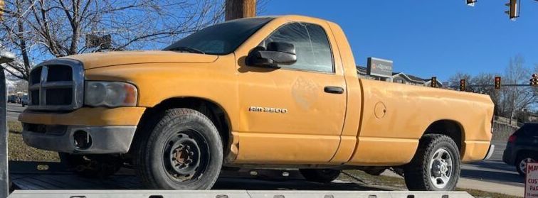 A yellow dodge ram truck is parked on the side of the road. | Wind River Auto Diesel