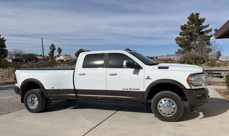 A white truck is parked in a driveway next to a house. | Wind River Auto & Diesel