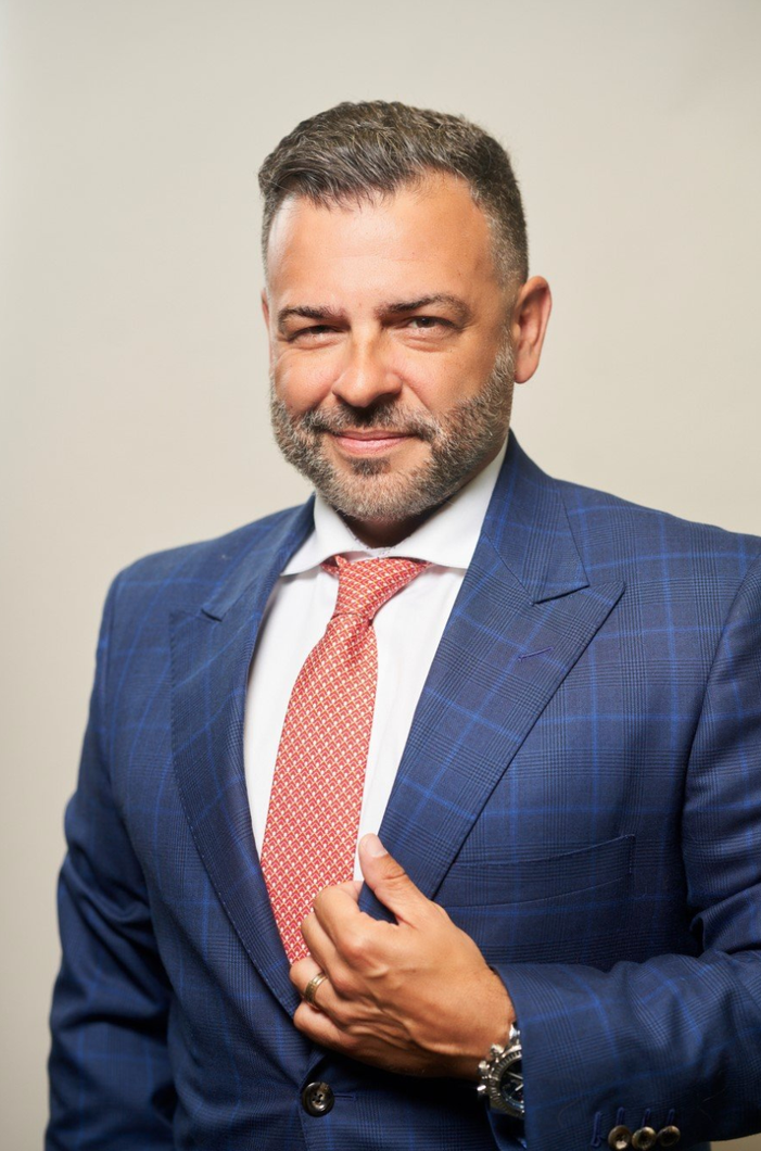 A man in a suit and tie is smiling for the camera