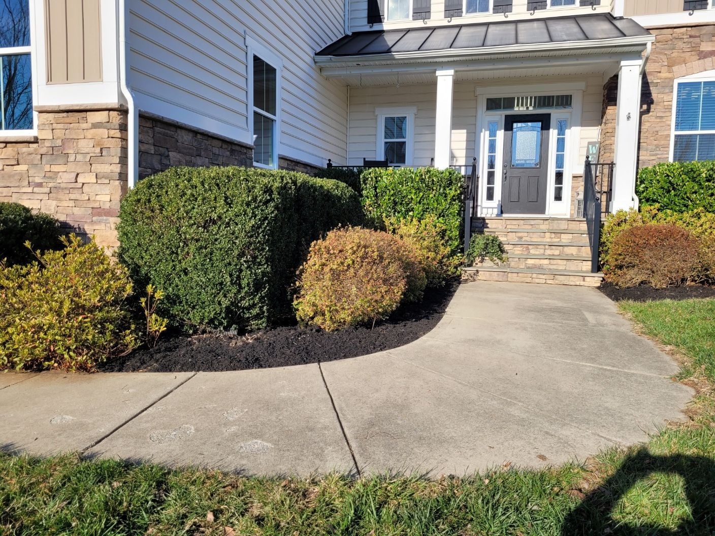 A concrete walkway leading to the front door of a house.