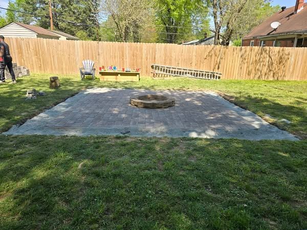 A fire pit is being built in the middle of a backyard.