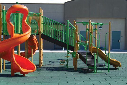 A playground with an orange slide and green stairs