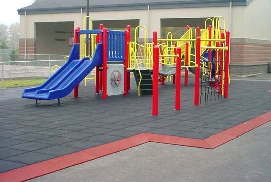 A playground with a blue slide and red poles